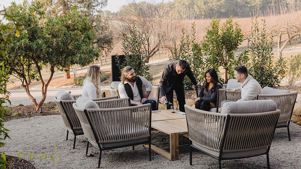 Waiter pouring red wine for group at Jada Vineyard