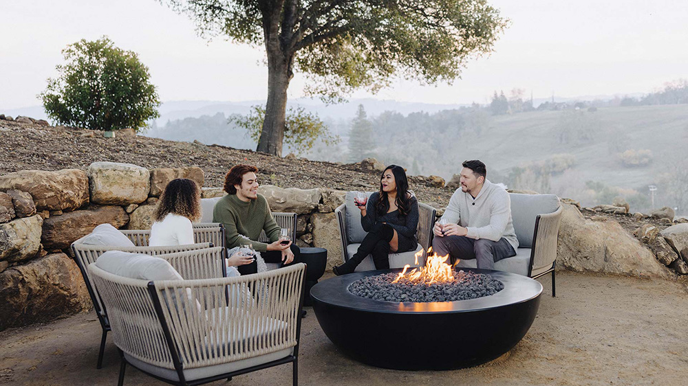 Group drinking wine by outdoor fire pit at Jada Vineyard